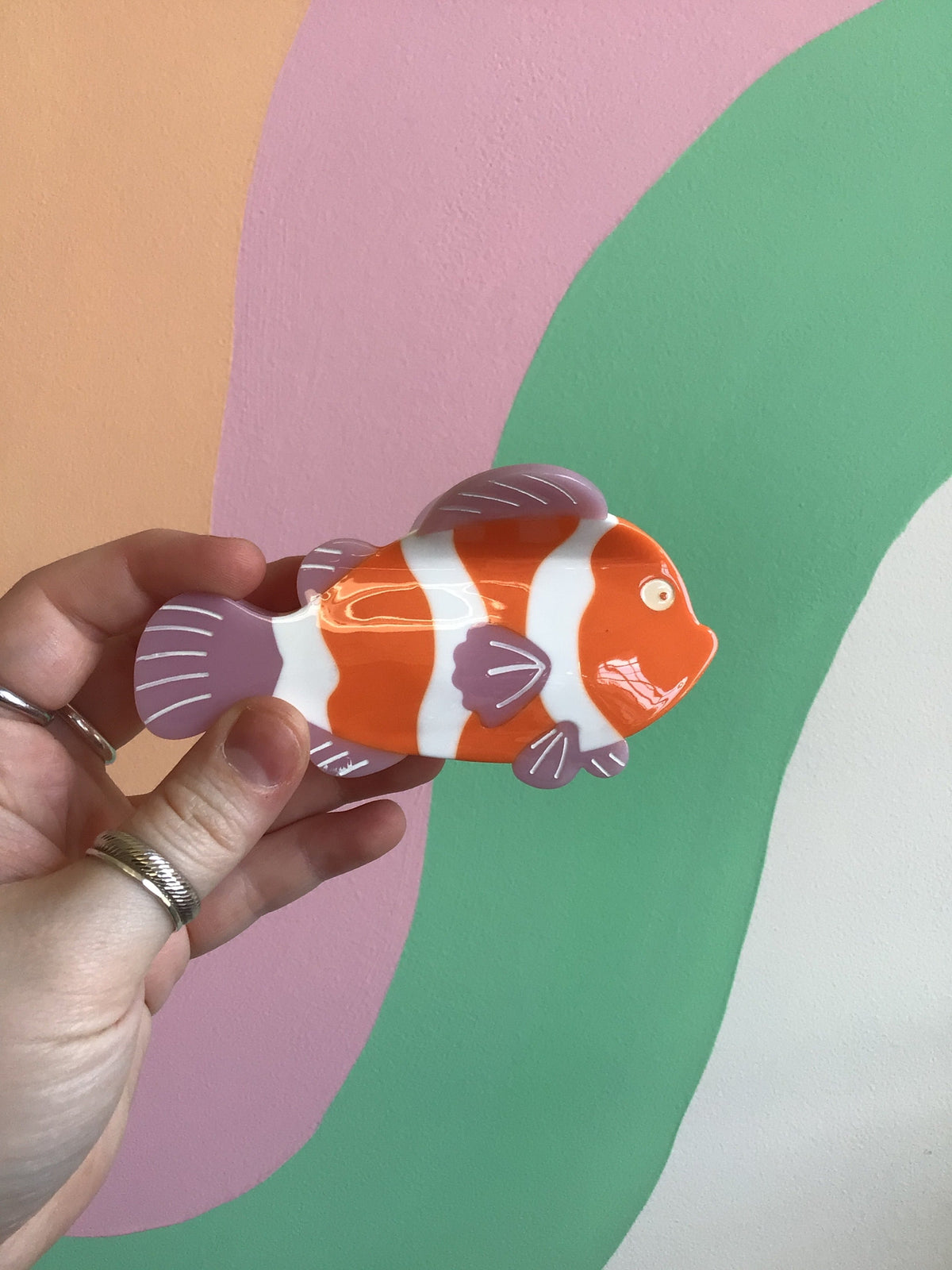 Orange-and-white striped fish-shaped hair claw with purple fin accents