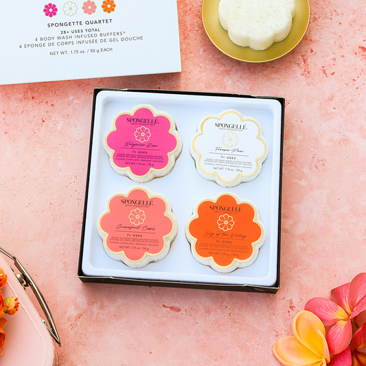 Open gift set box with four flower-shaped sponges in pink, white, coral, and orange.