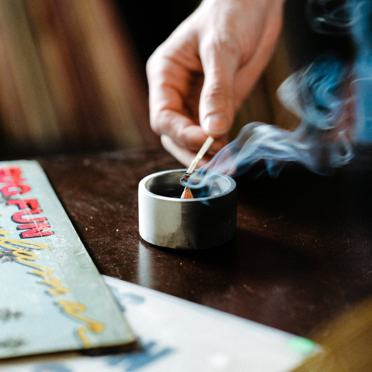 Round incense holder with burning incense cone and rising smoke, open top