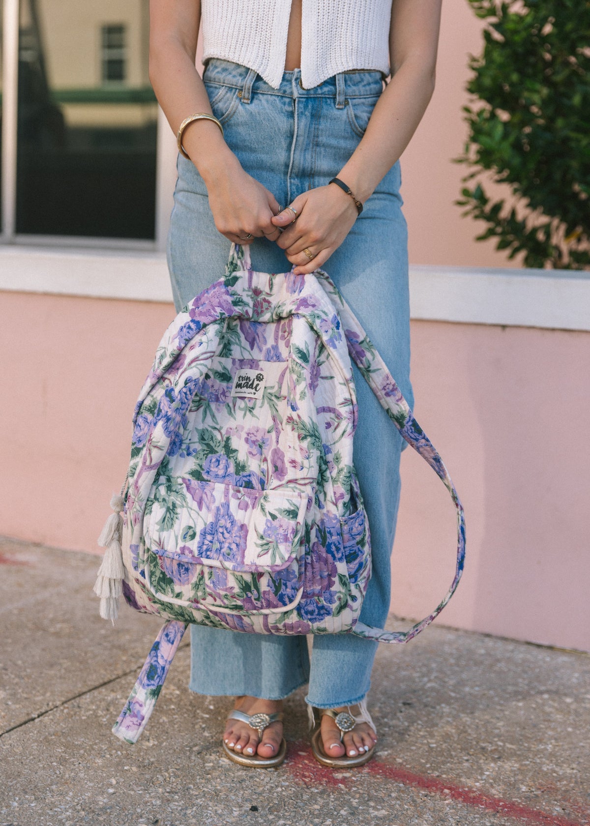 Quilted floral backpack tied at the top with two handles, tassel trim visible