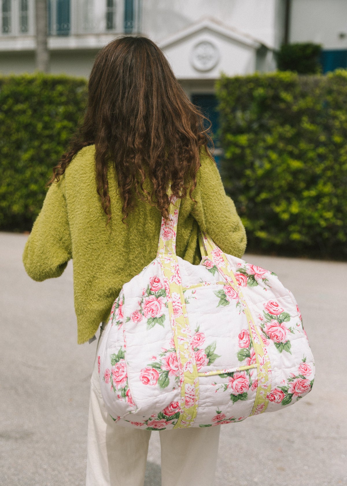 White floral duffle bag with green trim, drawstring top, and shoulder handles