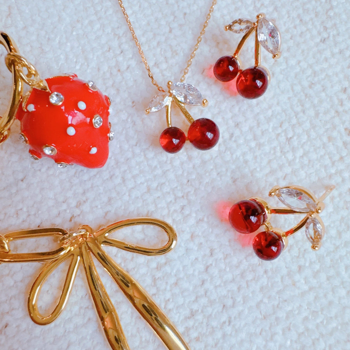 Strawberry bag charm set with red bead accents and gold heart-and-bow details