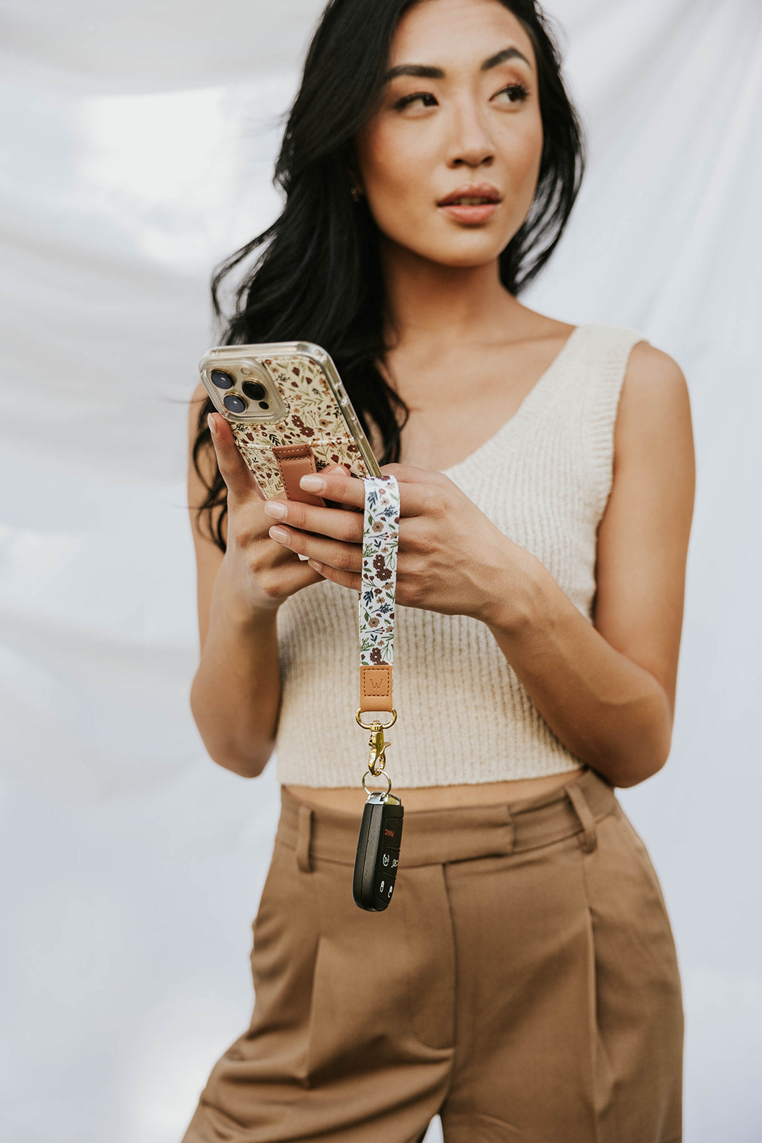 Wrist lanyard in floral print with tan strap and metal phone-ring clasp