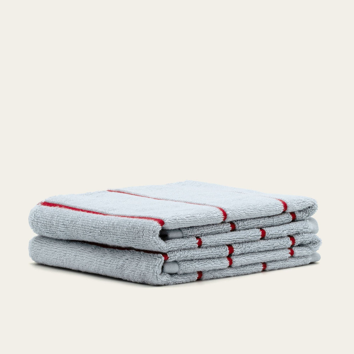 Stack of light gray cotton towels with red stripe accents