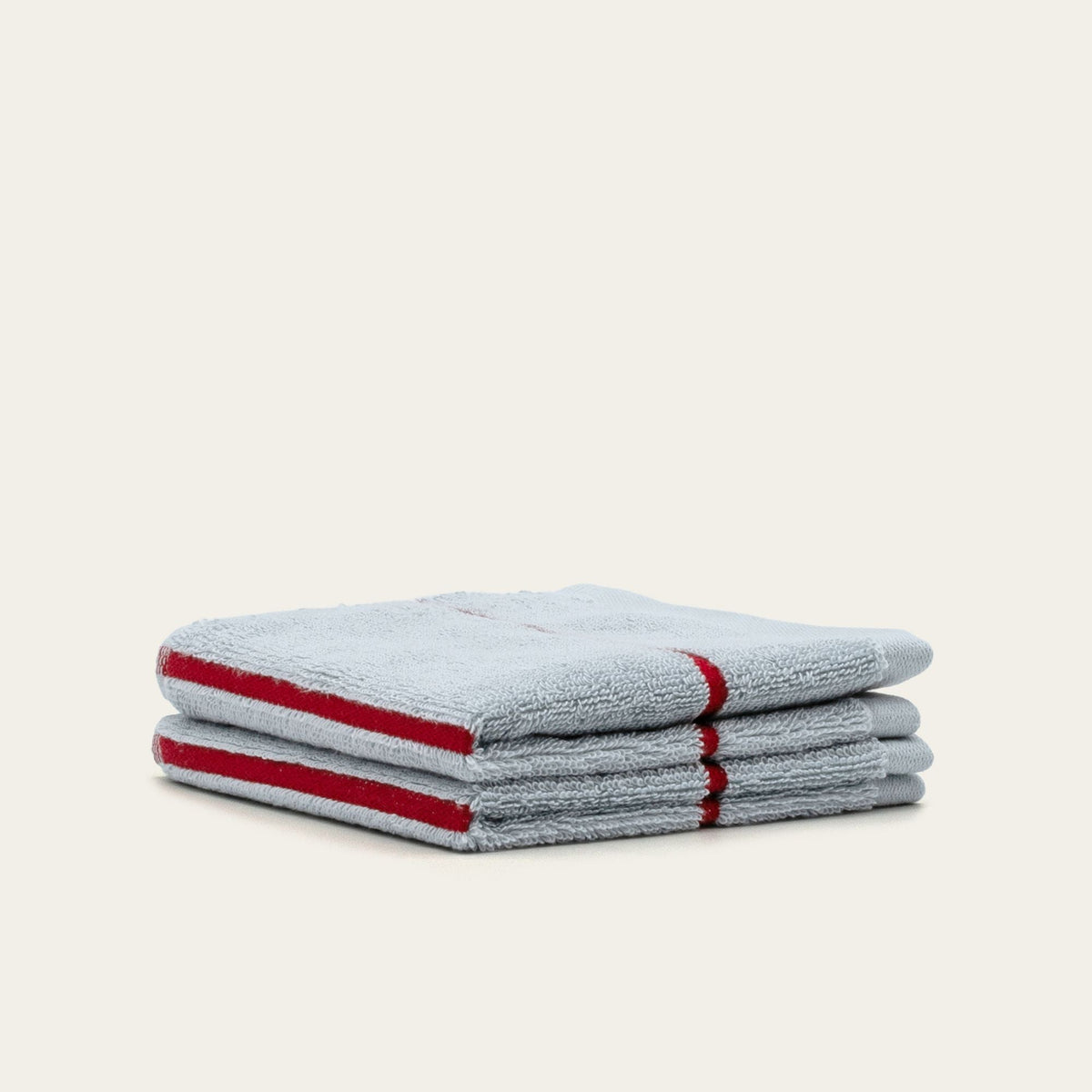 Two stacked light gray cotton towels with red stripe accents