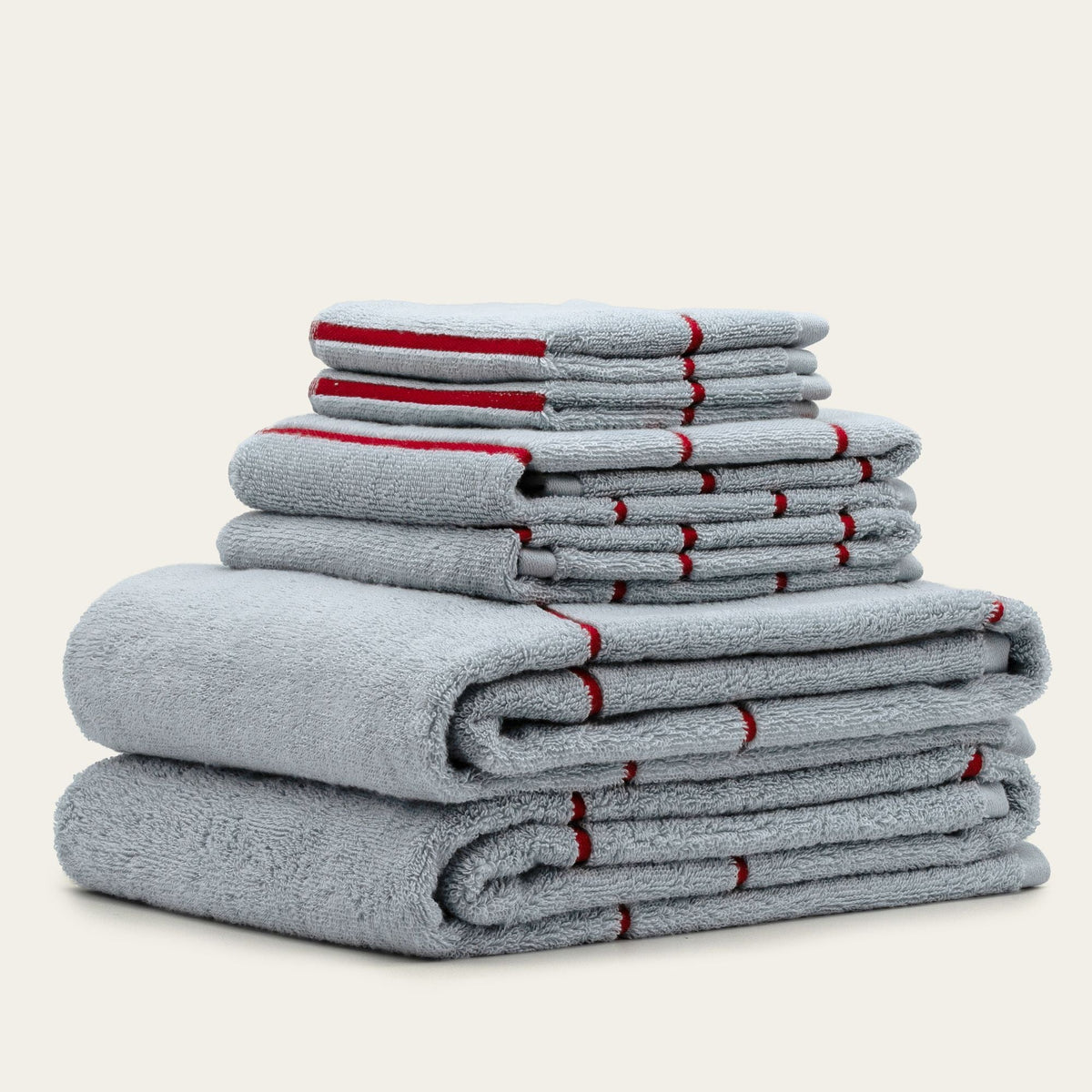 Layered light gray cotton towel set with red stripe accents