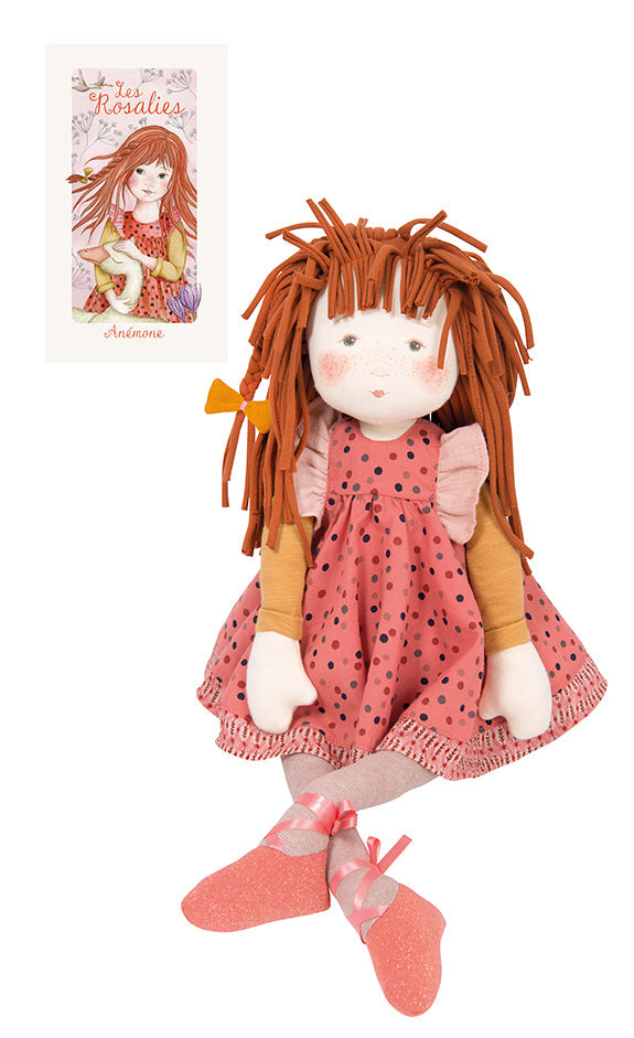 Anemone rag doll with long auburn yarn hair, pink polka-dot dress, and matching shoes, beside its card
