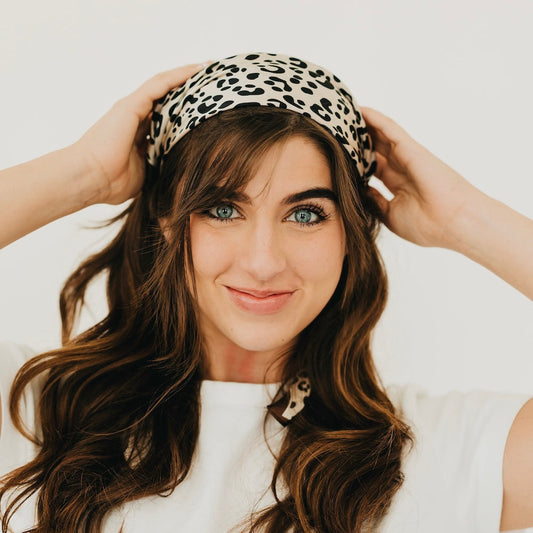 Leopard print square scarf with brown border, worn as a head scarf