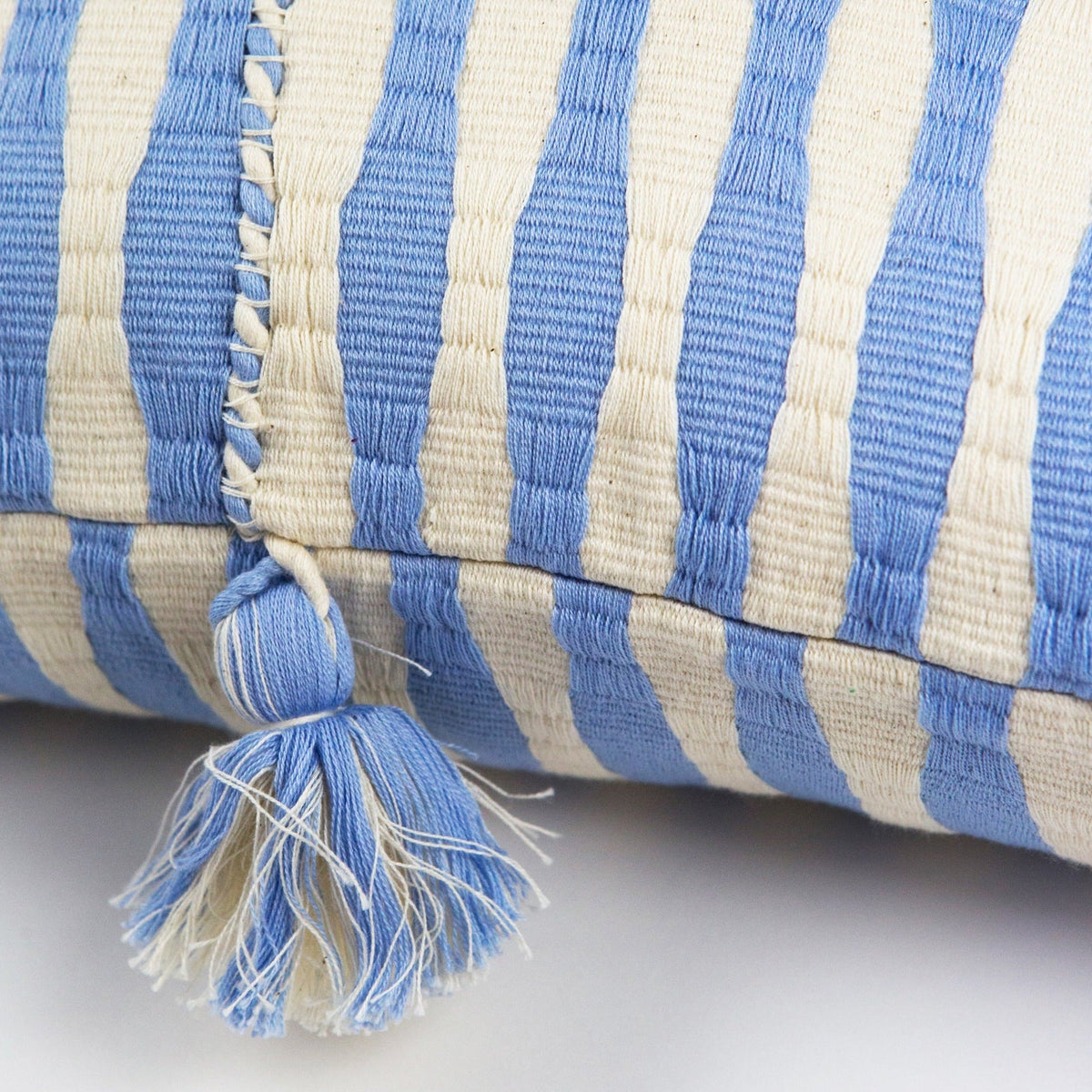 Blue striped pillow close-up showing braided tassel and stitched seam