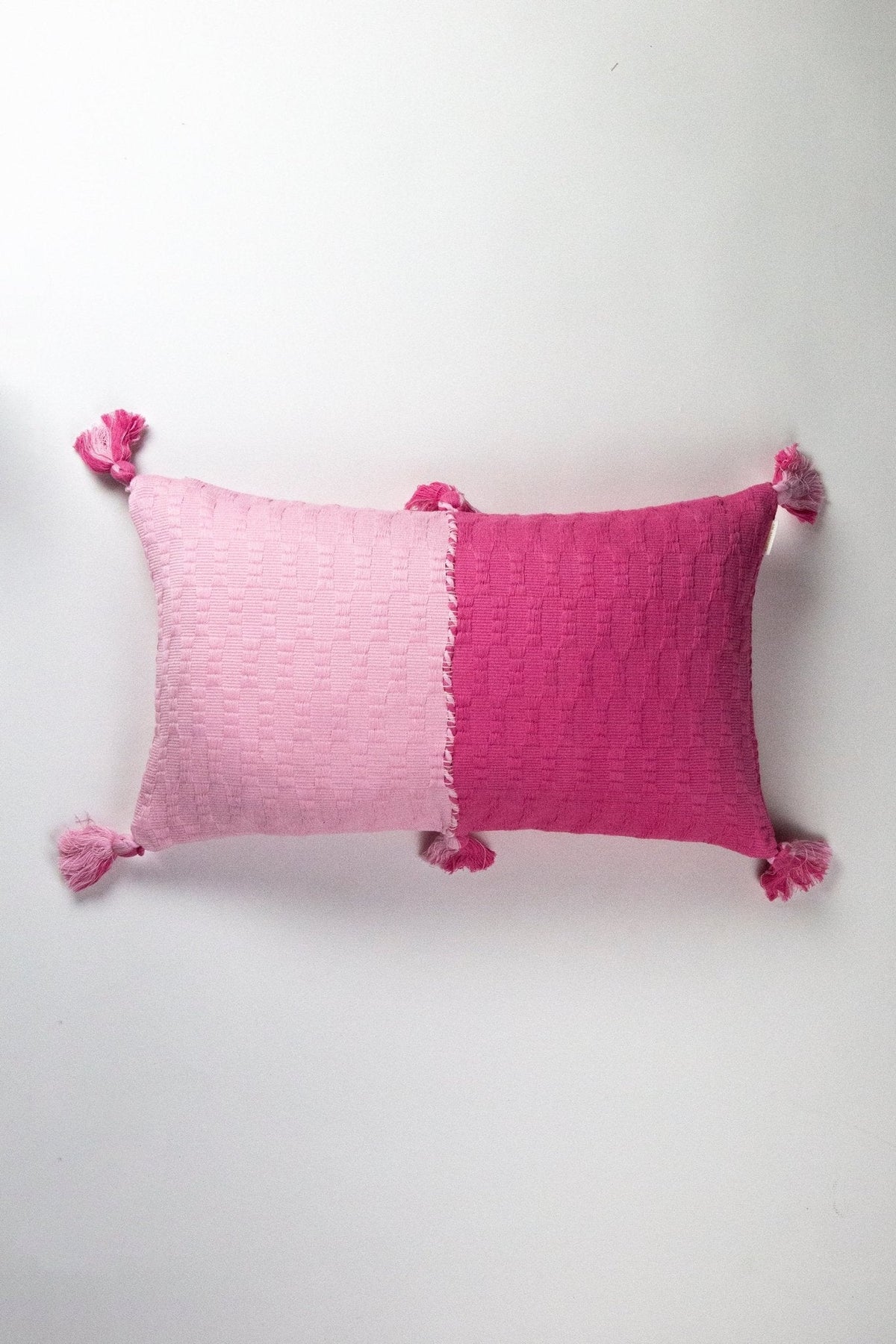 Pink colorblocked decorative pillow with tassel corners.
