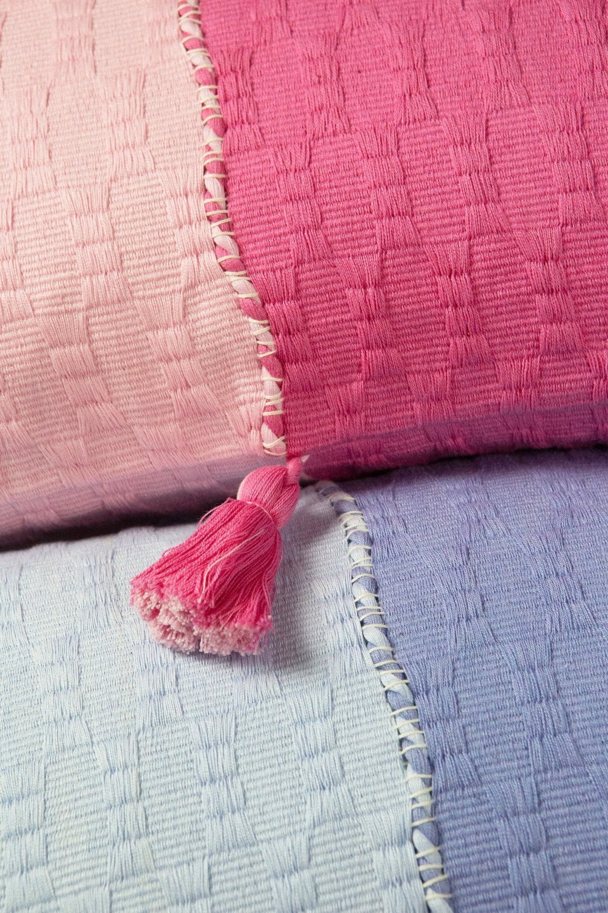Pink and periwinkle decorative pillows close-up with tassel trim.
