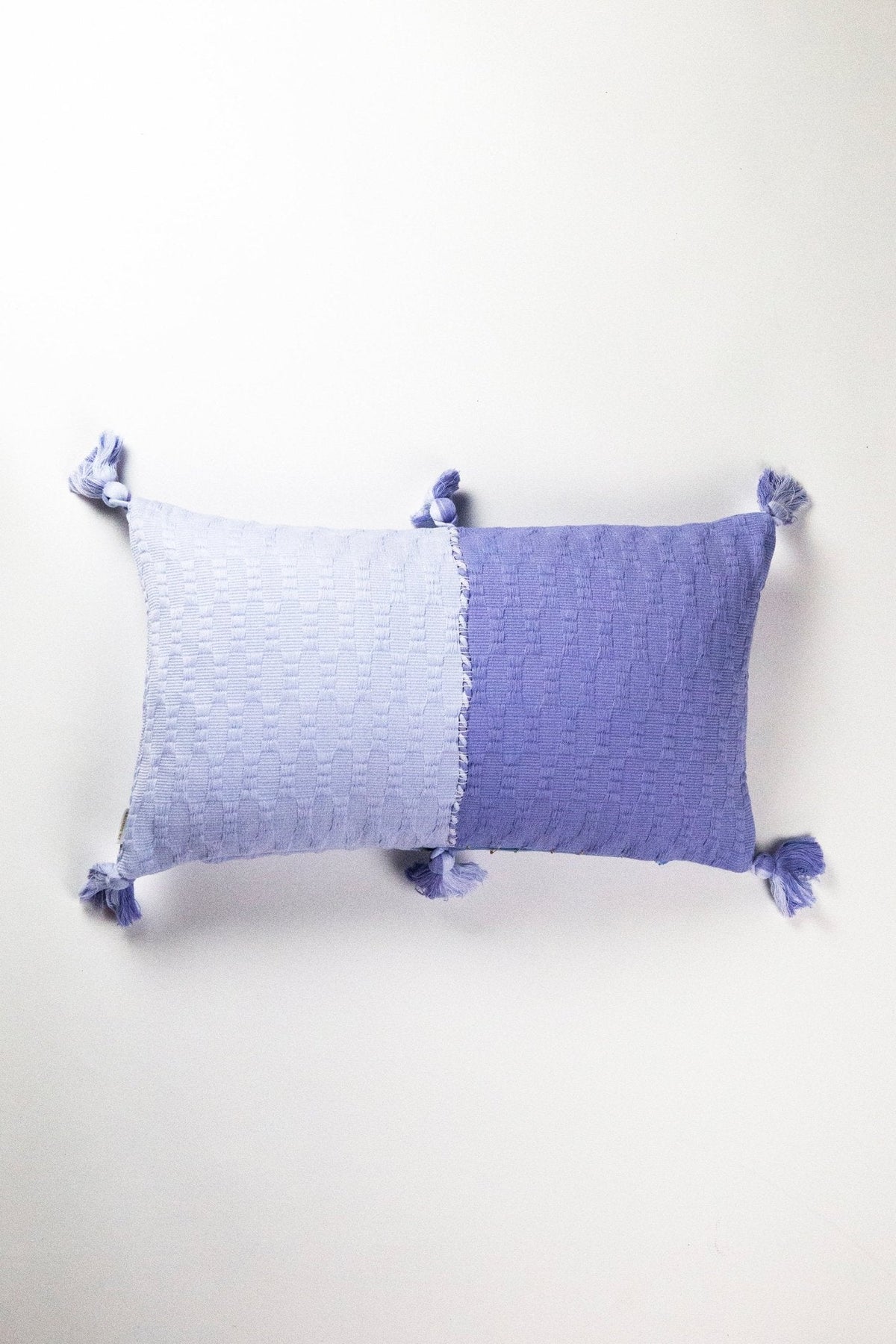 Periwinkle blue colorblocked decorative pillow with tassel corners.