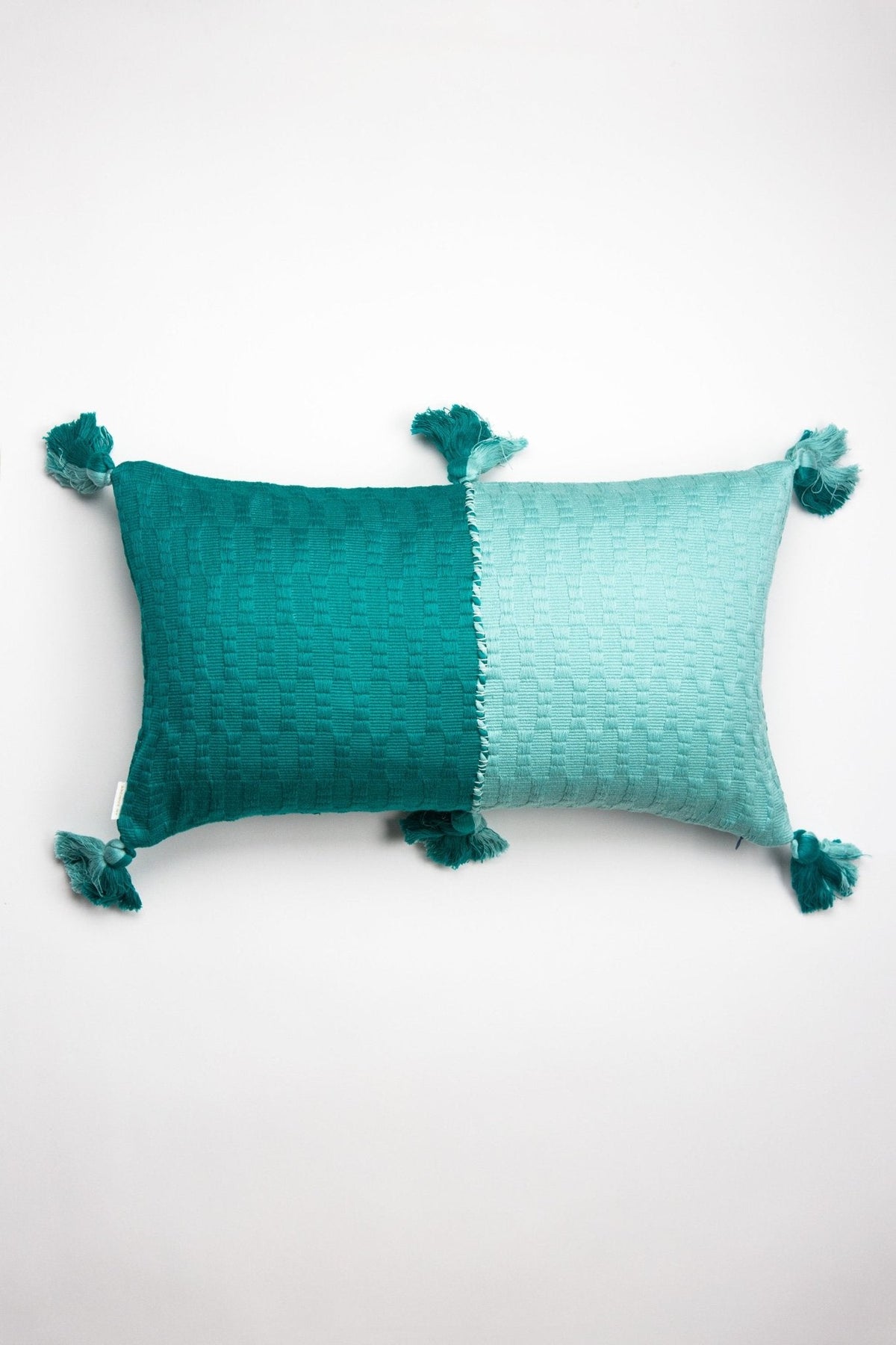 Two-tone teal throw pillow with textured weave and tassel corners