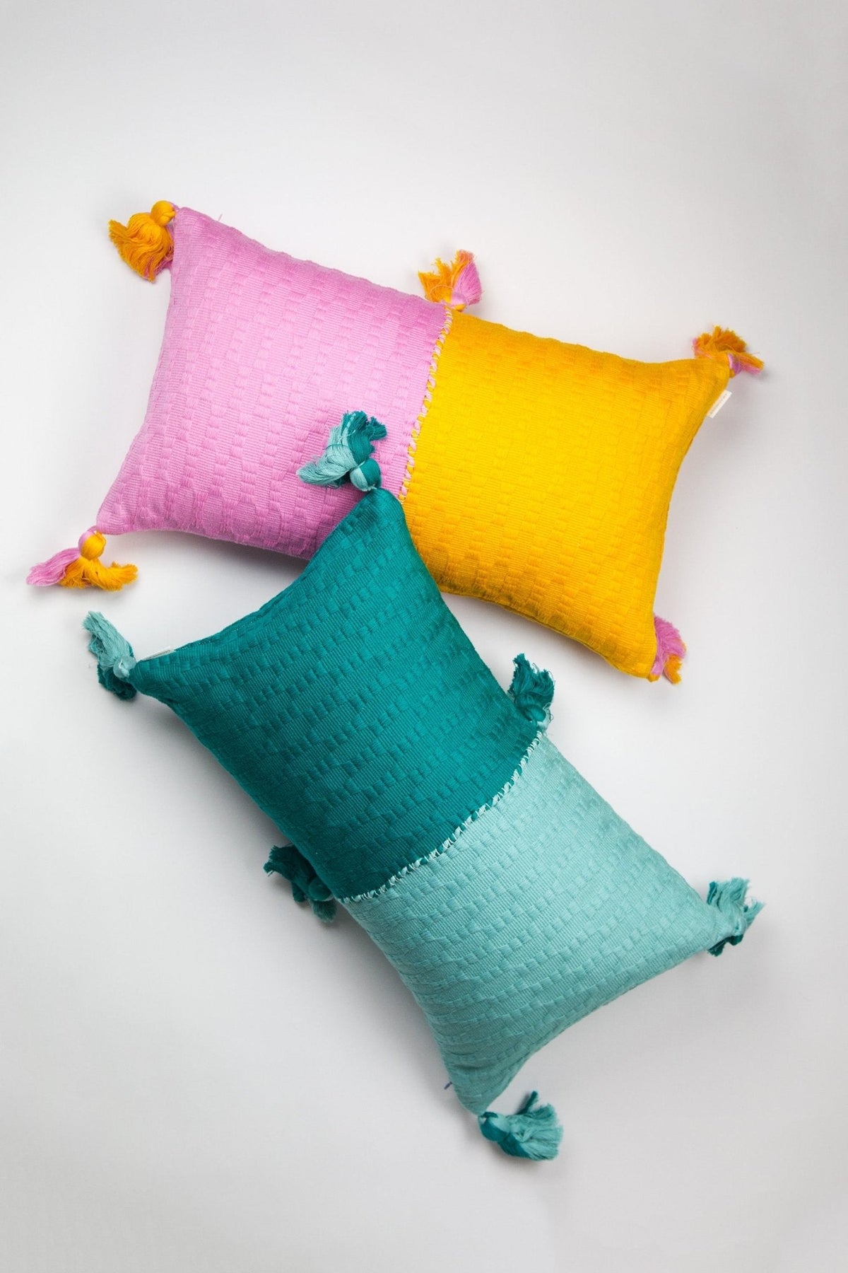 Colorblocked throw pillow with pink, orange, and teal panels and tassel corners