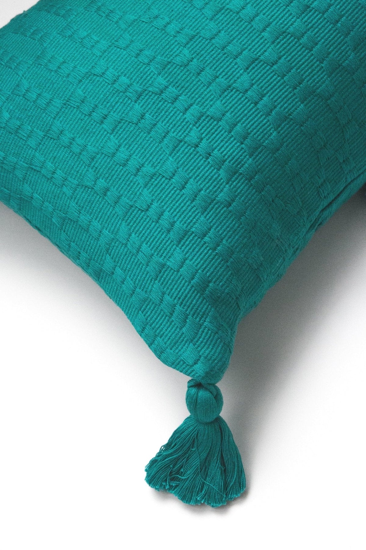 Teal textured throw pillow corner with tassel knot trim