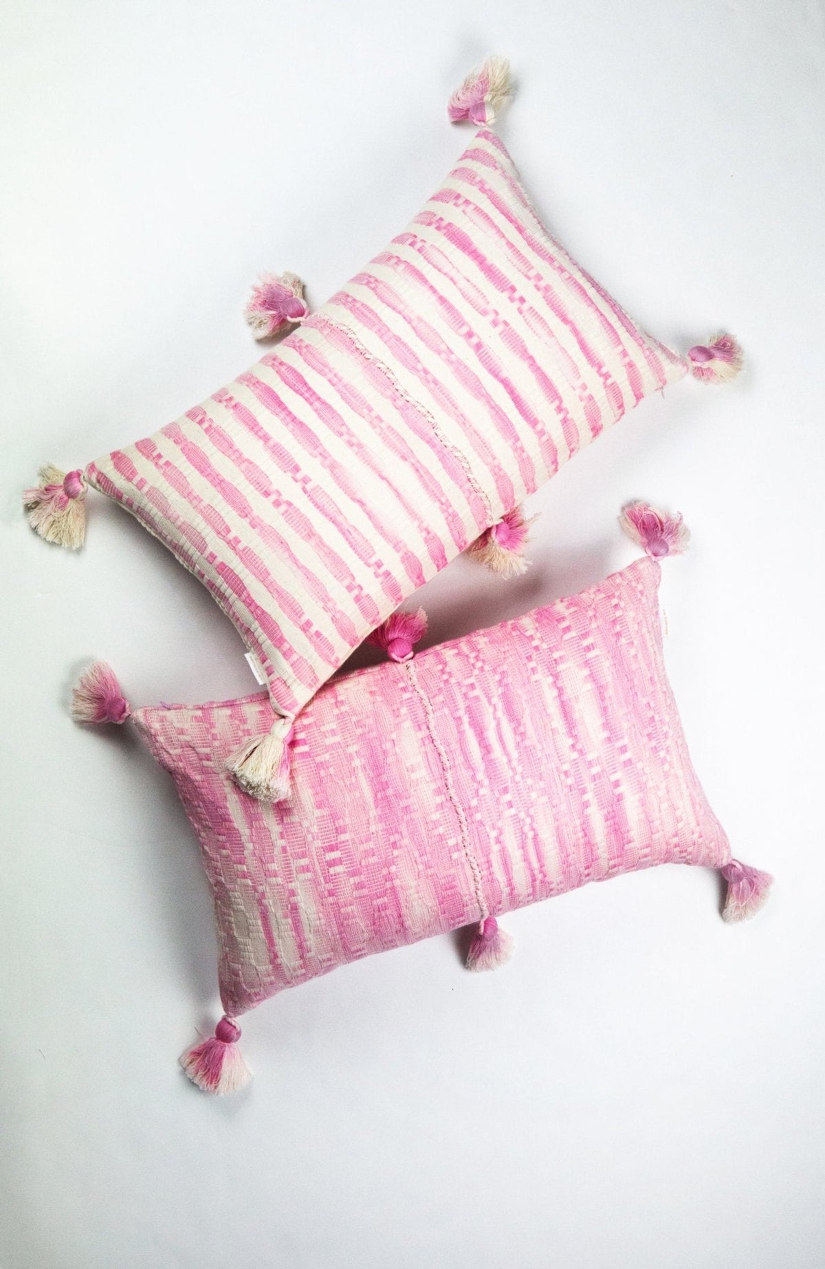 Faded pink striped throw pillow with corner tassel pom-poms