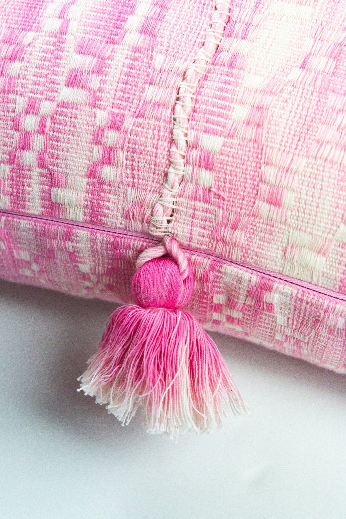 Faded pink striped pillow detail with looped tassel fringe