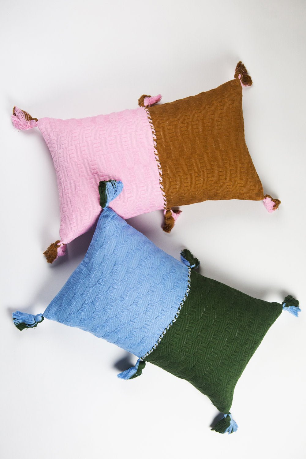 Set of square throw pillows in pink, umber, blue, and green with tassel corners