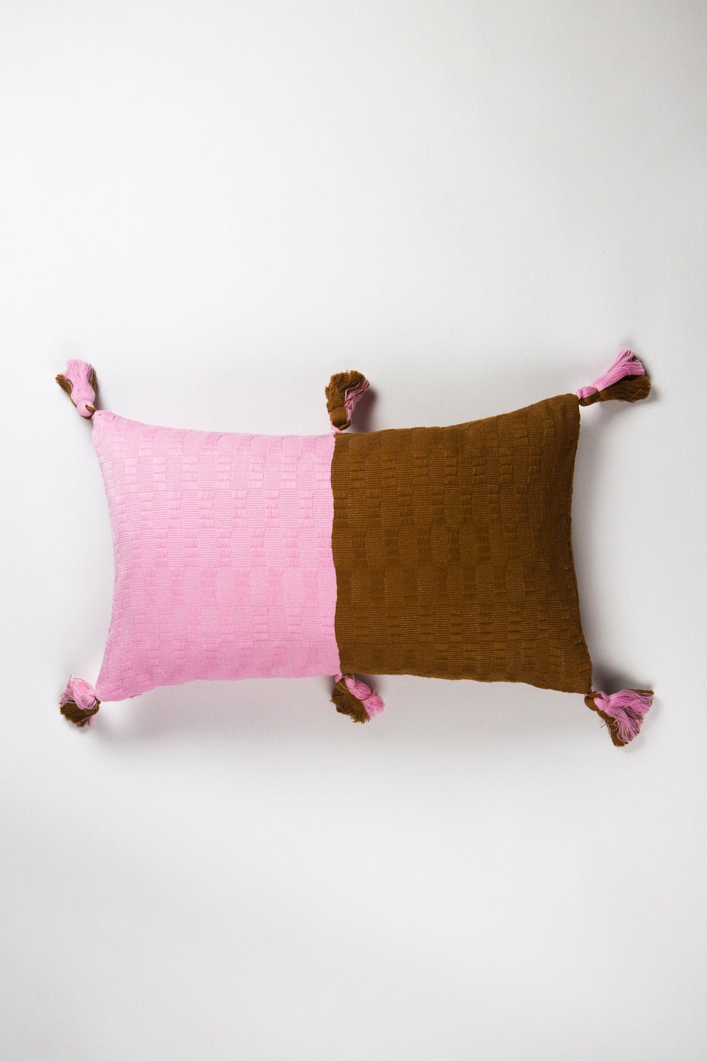Colorblocked square throw pillow in baby pink and umber with tassel corners