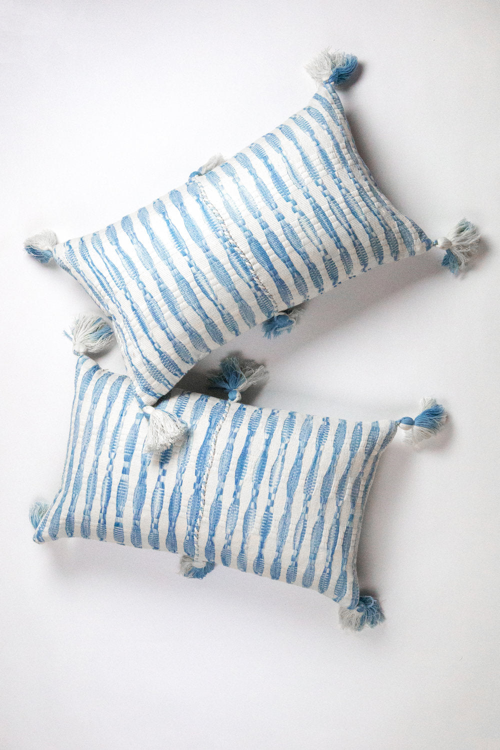 Two faded indigo stripe pillows with corner tassels