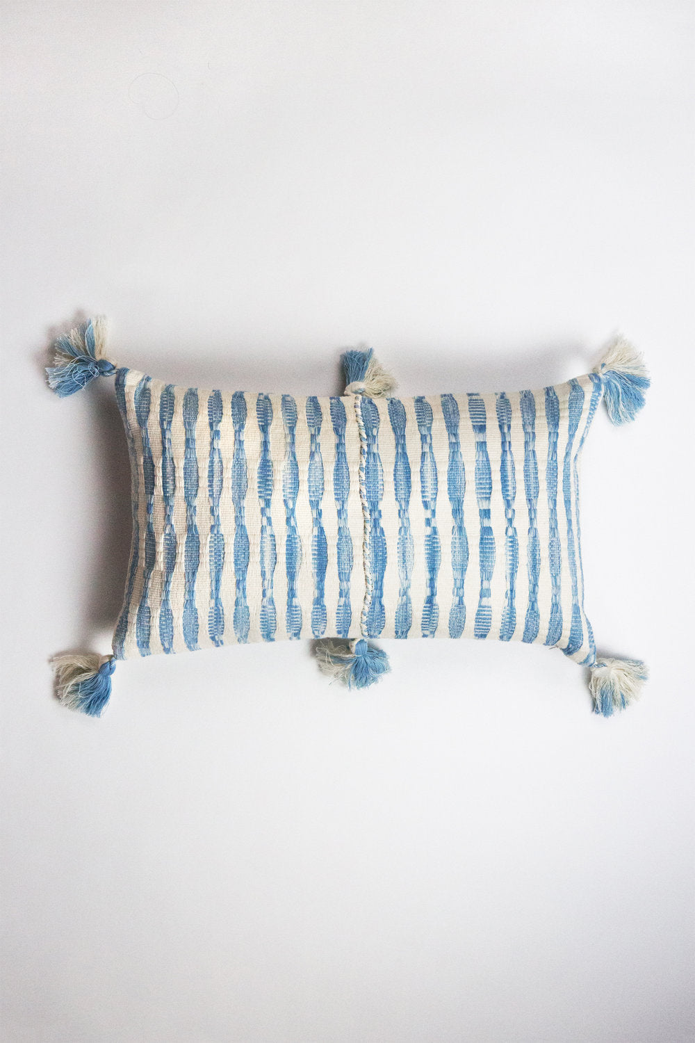 Rectangular blue and white striped pillow with tassels at all four corners