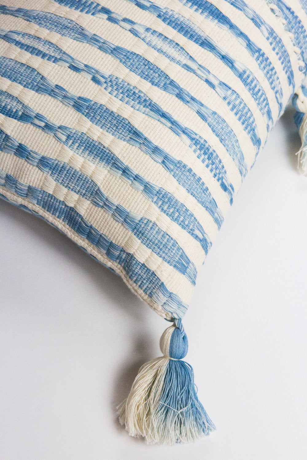 Blue-striped pillow detail with corner tassel and knotted trim