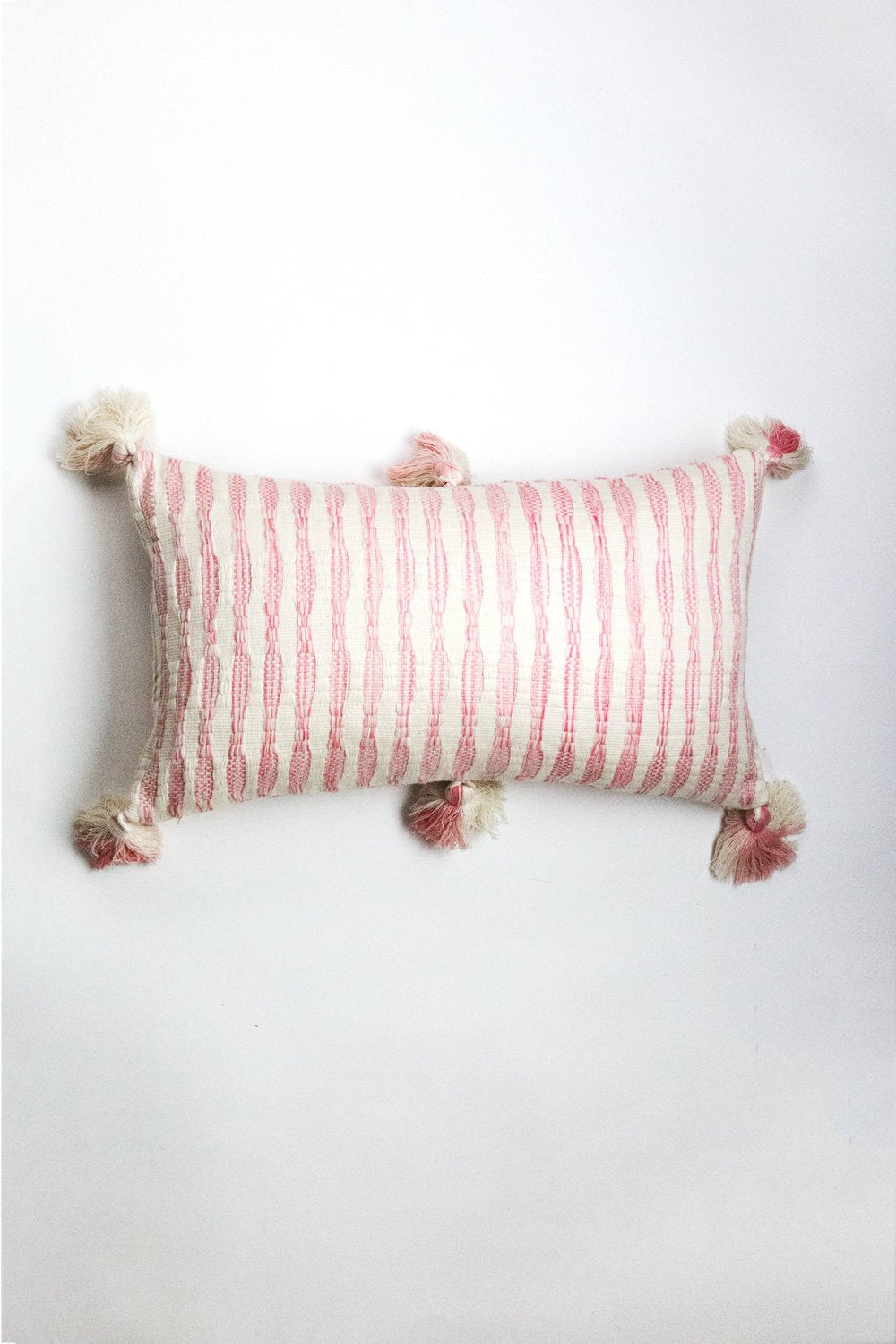 Faded pink striped lumbar pillow with corner tassel pom-poms
