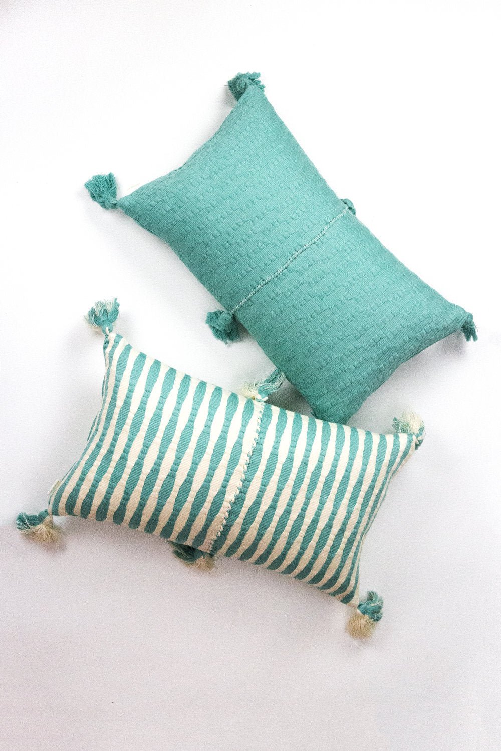 Faded aqua textured throw pillow with tassel corners and center seam