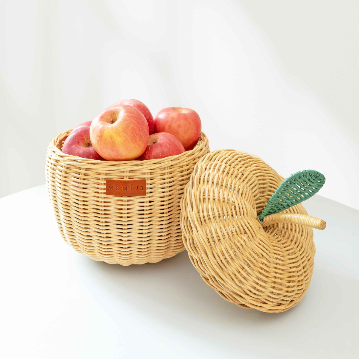 Natural rattan apple basket filled with apples, shown beside its woven lid
