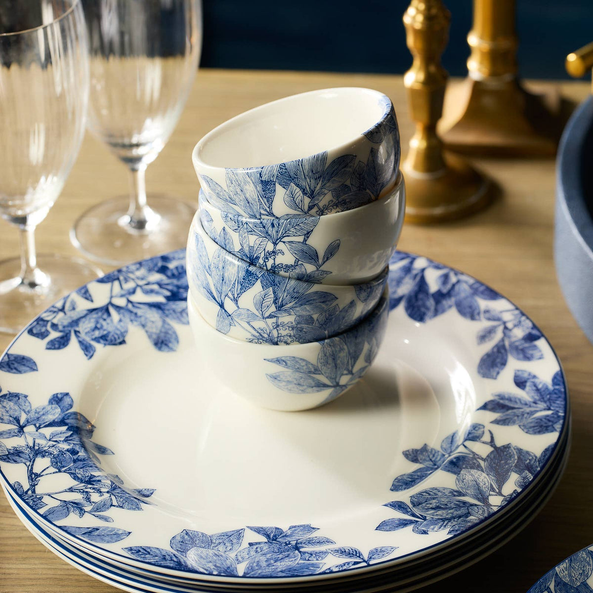 Round porcelain saucer-style plate with blue botanical rim, holding stacked cups
