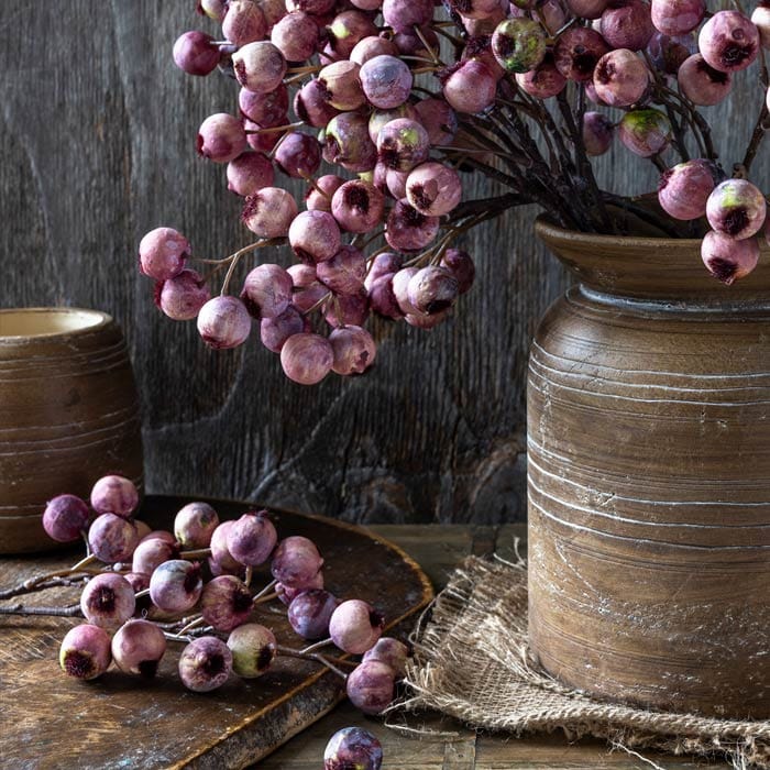 Faux hawthorn berry branches with purple-pink berries arranged in a vase
