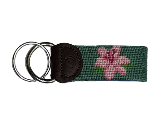Green woven key fob with pink flower, brown leather tab, and metal key rings