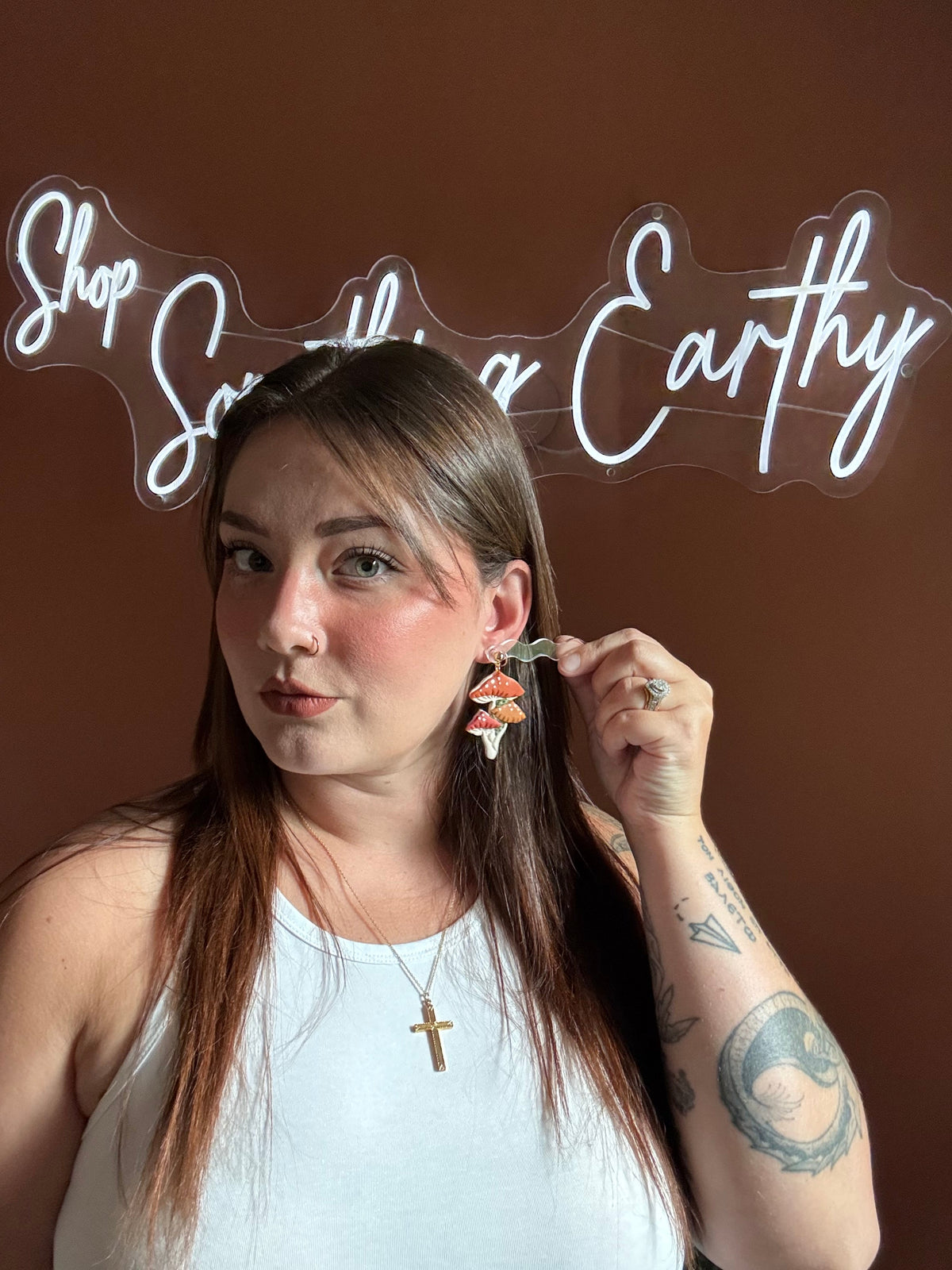 Mushroom stud earrings with orange-red caps and white gills, worn on model