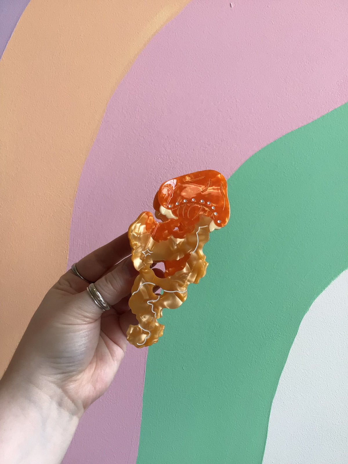 Orange jellyfish hair claw with golden accents and ruffled tentacles