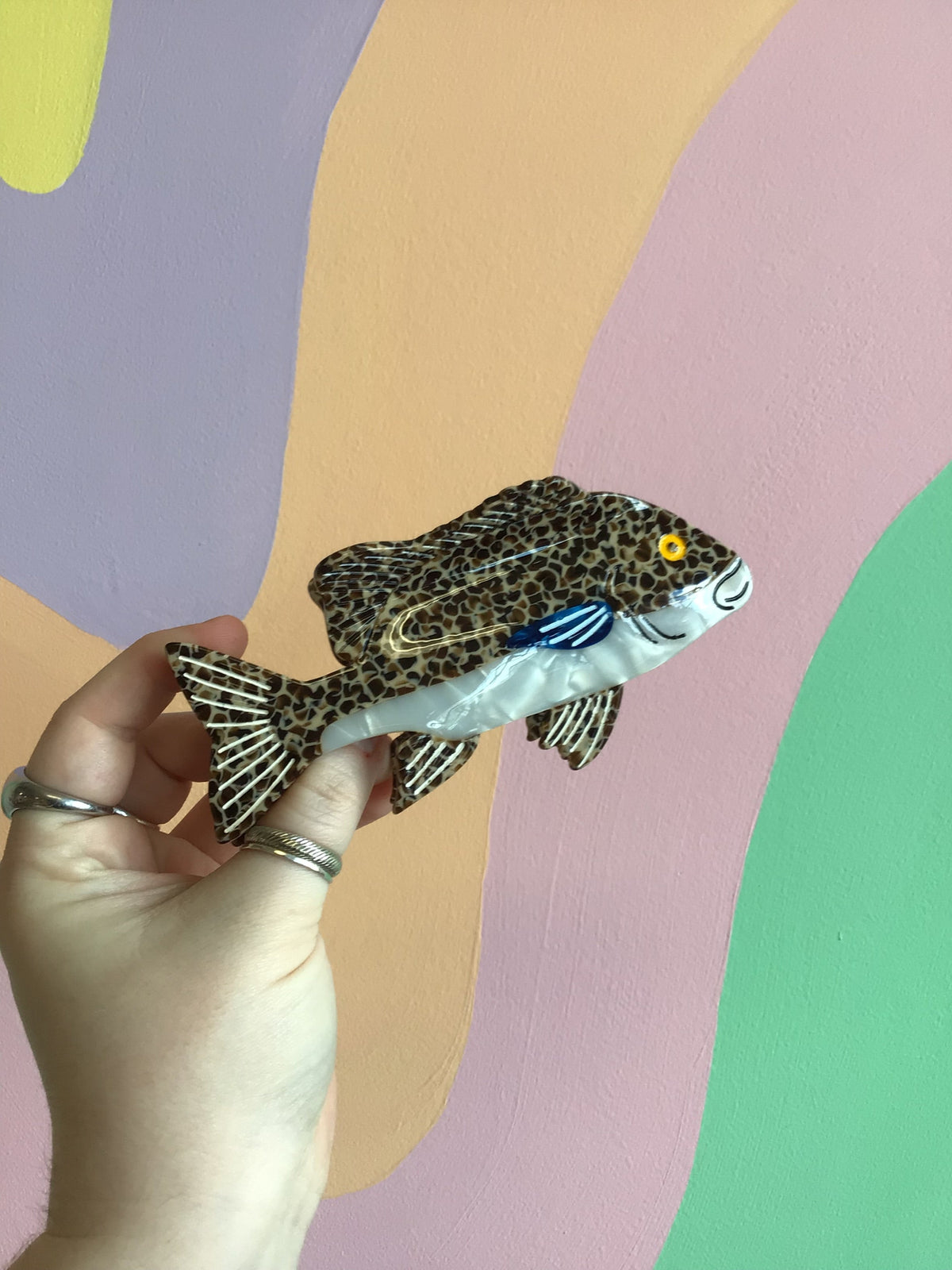 Fish-shaped hair claw, leopard-print head and body with blue underside and yellow eyes