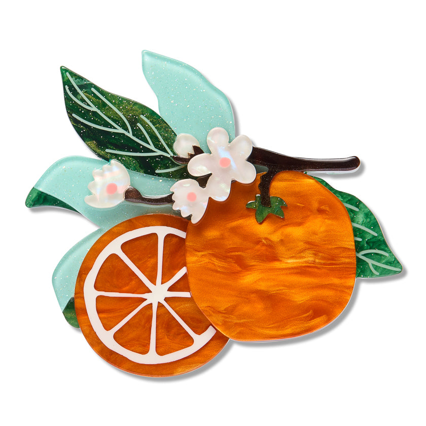 Erstwilder orange fruit brooch with citrus slice, white flowers, and green leaf details