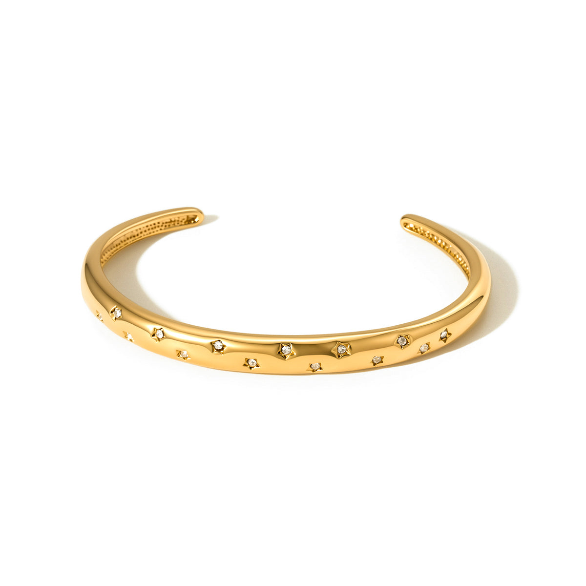 Gold-tone cuff bangle with star and stone detail pattern, wide view