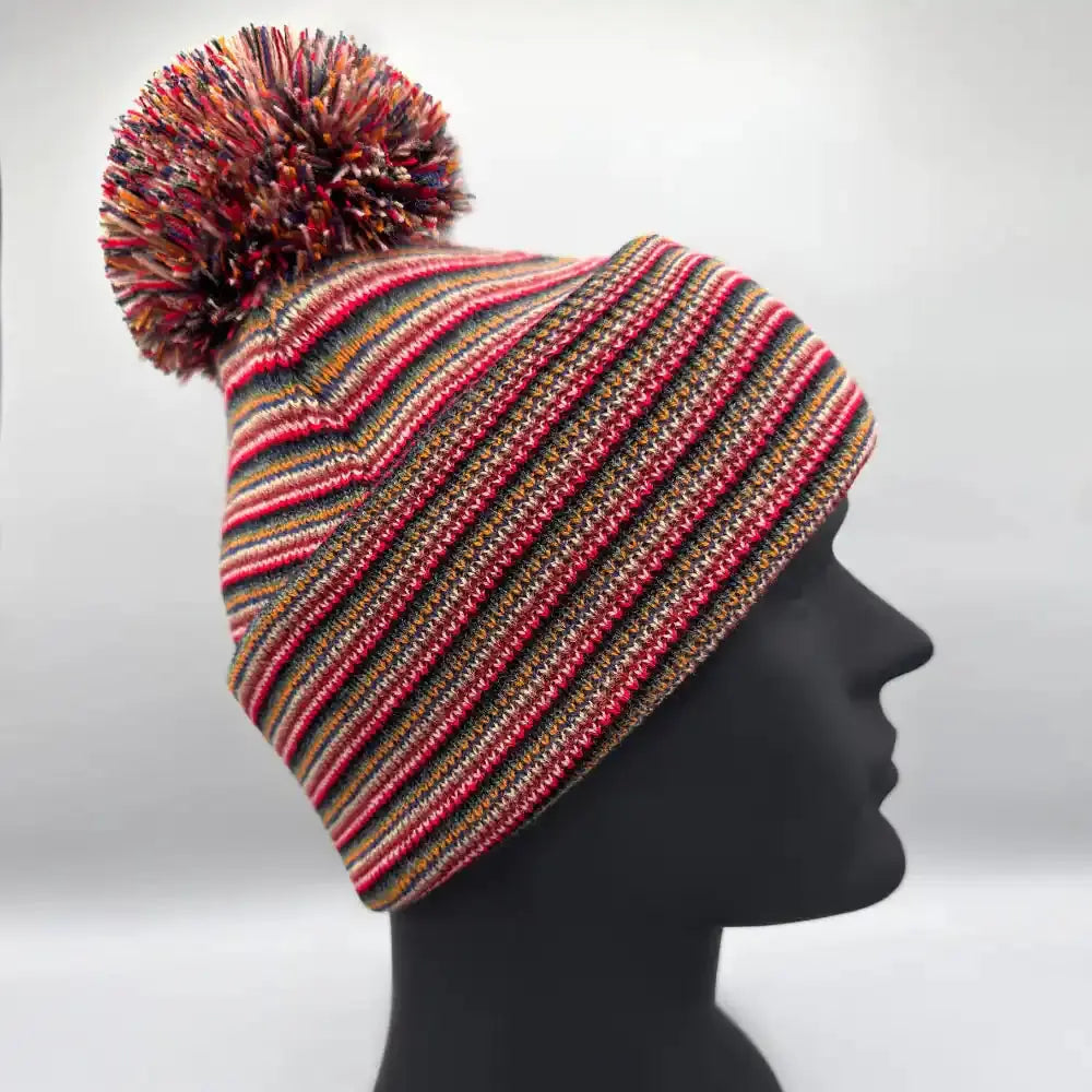 Multicolor striped knit beanie with pom pom, worn on head form