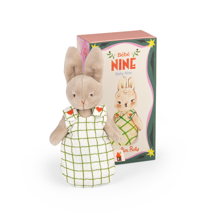 Plush rabbit doll in a white dress with a green grid and red flower details, beside its box