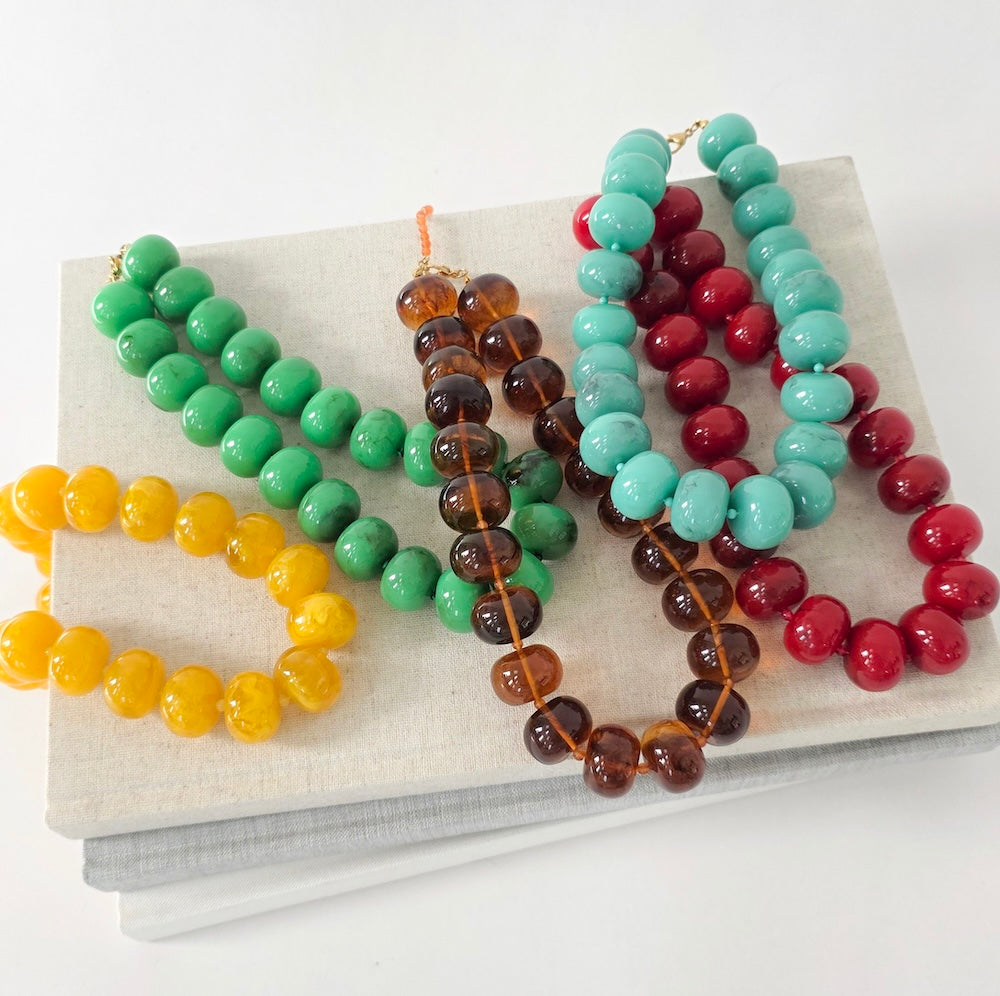 Set of colorful beaded necklaces with green, amber, teal, and red round beads