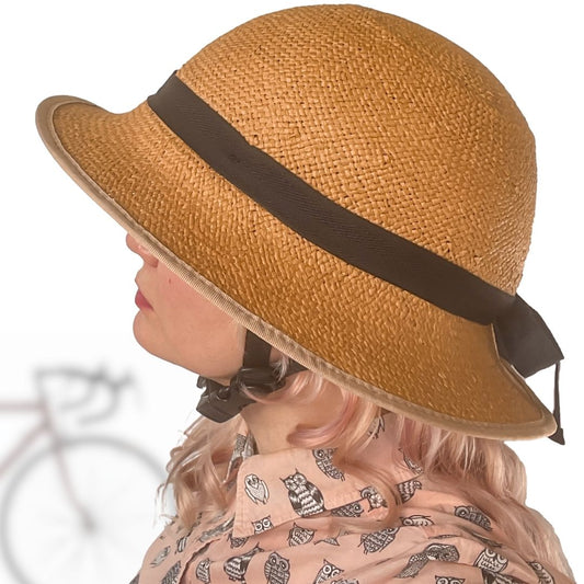Straw bike helmet cover, tan woven hat with black chin-strap clips