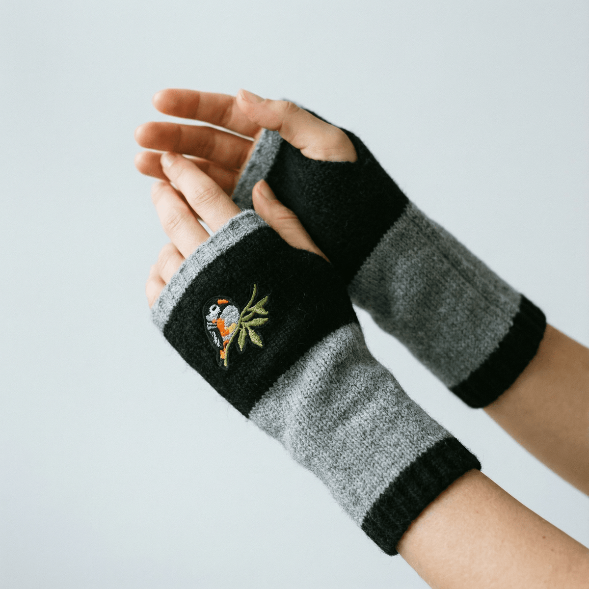 Black and gray knitted arm warmers with bird applique and ribbed cuffs