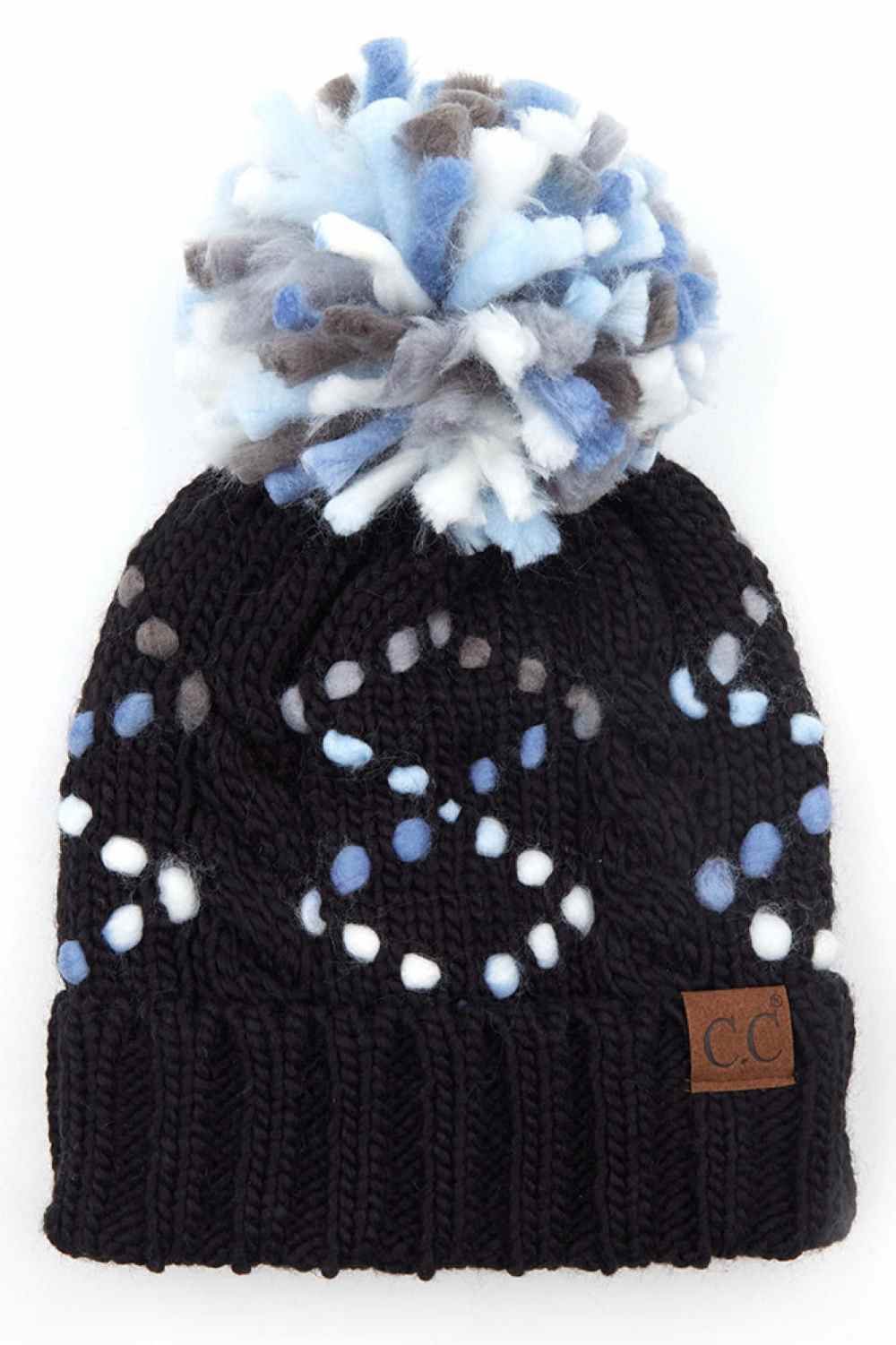 Chunky black knit beanie with blue-and-white dot pattern and faux fur pom-pom