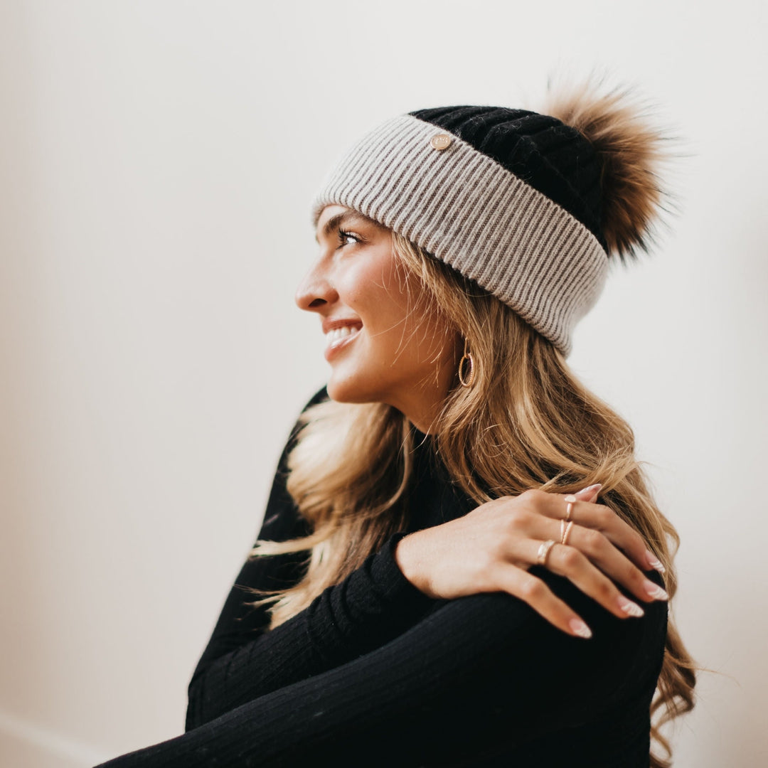 Two-tone knit beanie with tan fur pom; gray ribbed body and darker cuff