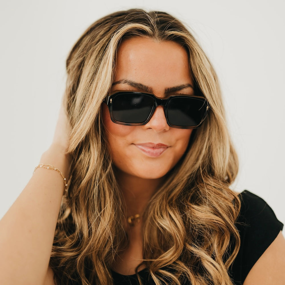 Tortoise-and-black square sunglasses with dark lenses, worn by a woman.