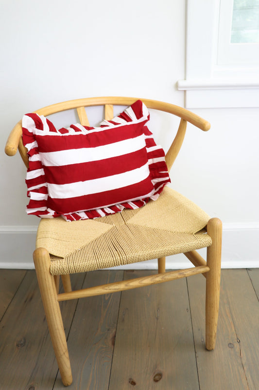 Red and white striped throw pillow with ruffled edges, shown on a chair