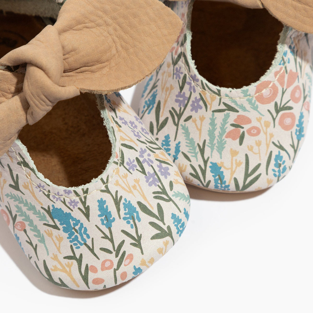 Baby floral baby shoes closeup showing tan knotted bow and stitched openings