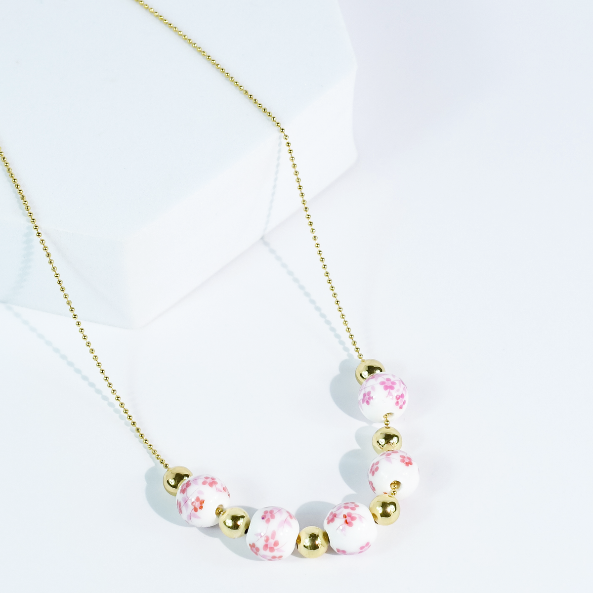 Gold-tone beaded necklace with pink floral round beads and gold accents