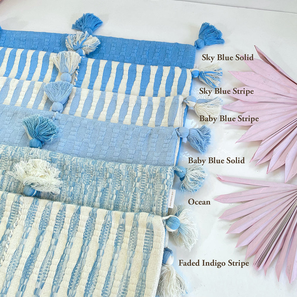 Stack of blue striped and solid throw pillows with corner tassels