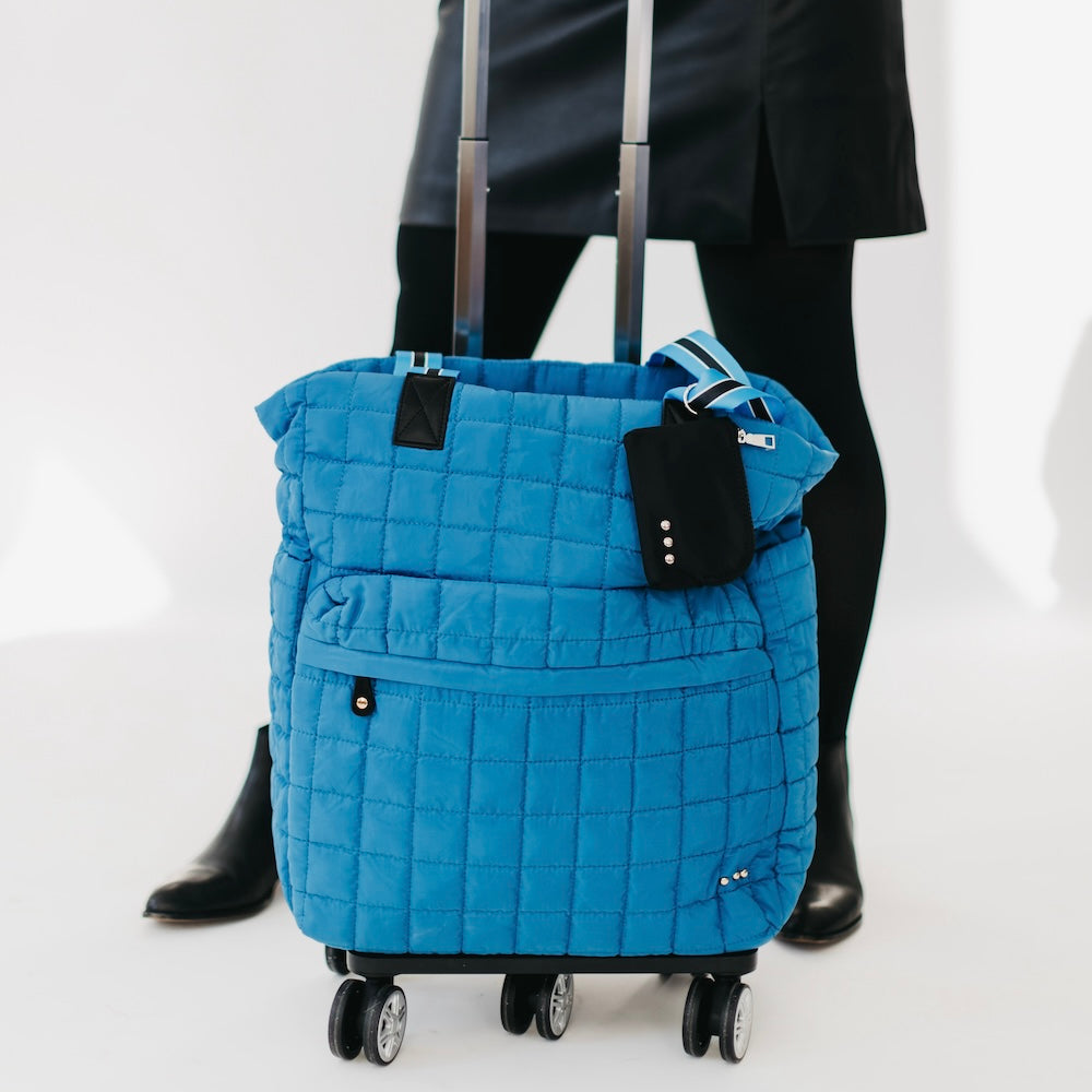 Blue quilted tote roller bag with wheels, front pocket, and zip top